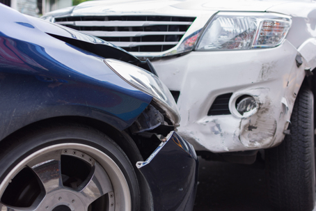 Two vehicles involved in a front-end collision with visible bumper and body damage after a car accident.