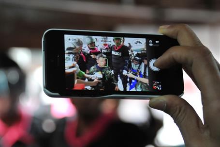 Alt text: Person holding smartphone capturing police officers in action, displayed clearly on the phone screen.