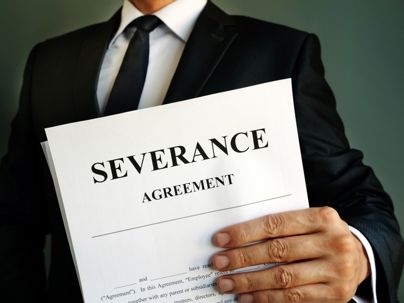 Business professional holding a document labeled “Severance Agreement,” symbolizing employee termination, exit terms, or workplace separation.