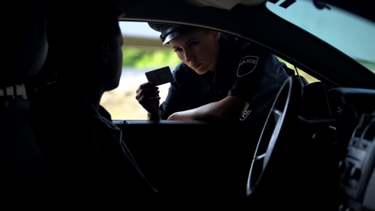 Police officer asking a driver for identification during a traffic stop inside a car
