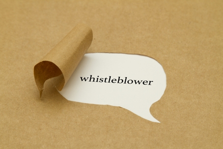 A brown paper surface peeled back to reveal the word "whistleblower" printed in black text inside a speech bubble shape.
