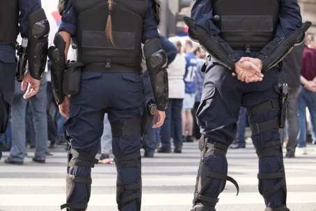 Image of the backside of police officers, standing in front of a crowd of people
