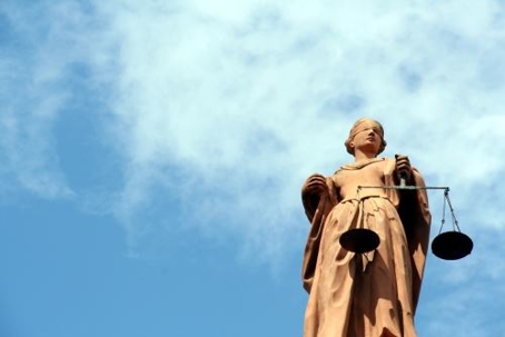 Image from the perspective of looking up at a Lady of Justice statue and the sky